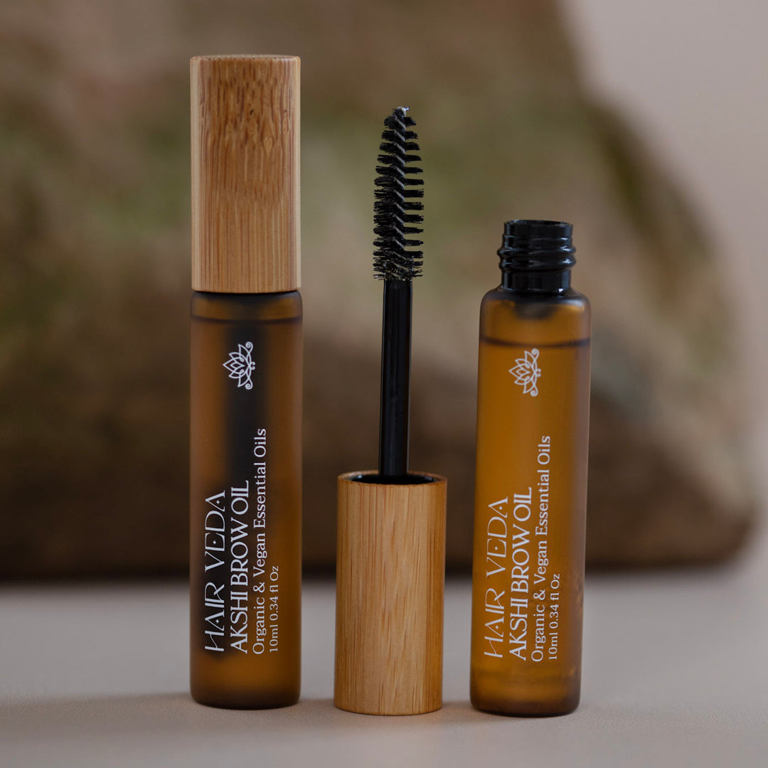 A mascara bottle next to a brush, highlighting makeup tools for enhancing eyelashes.