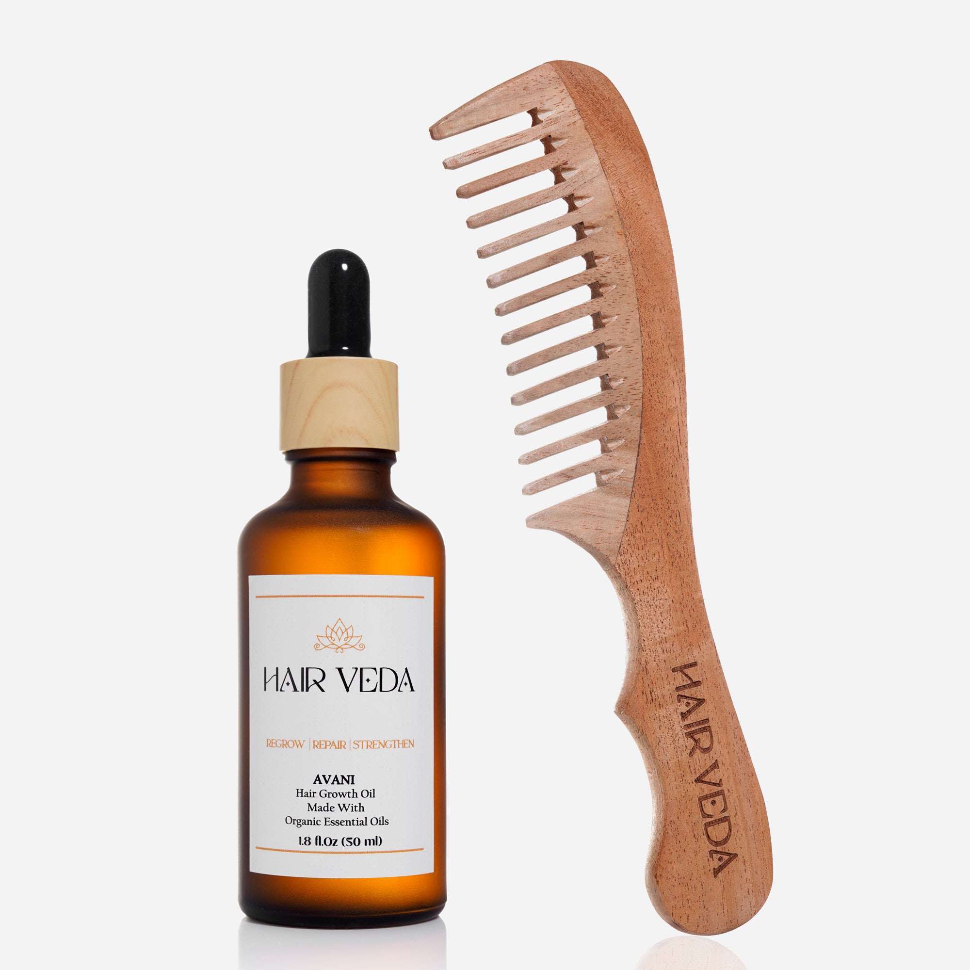A bottle of hair oil beside a wooden comb and hair clips on a white background.