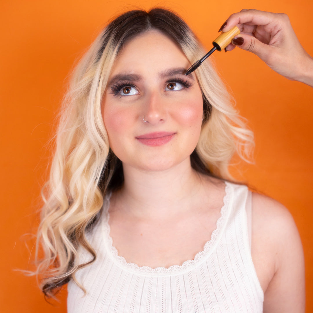 A blonde-haired woman is receiving an eyebrow grooming treatment.
