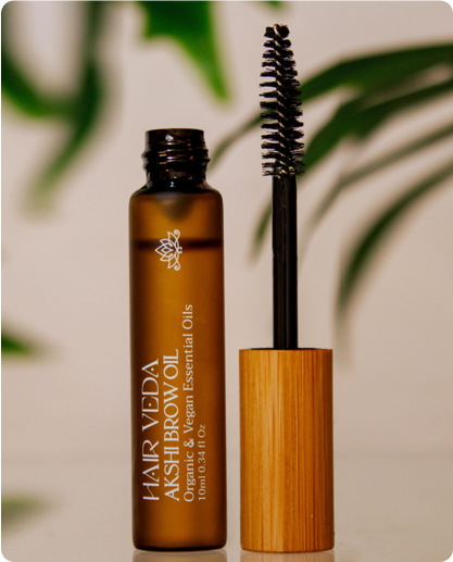 A bottle of Akshi brow oil with a mascara brush placed beside it, showcasing the product's design and functionality.